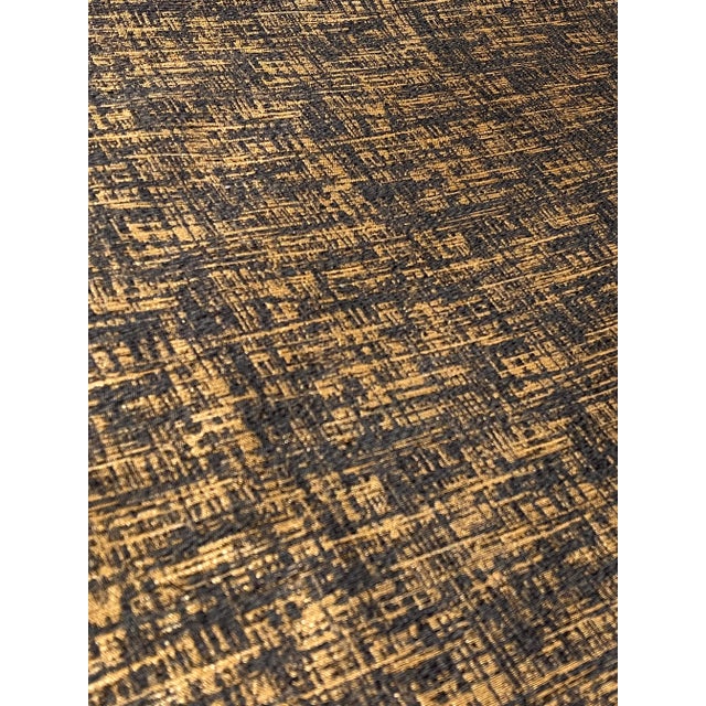 This abstract modern fabric by caracole has a metalic gold and charcoal cross hatch design. It is woven and has a medium...