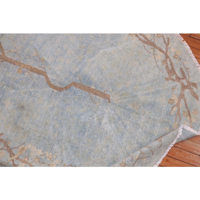An oval-shaped worn early 20th century Chinese rug in powder blue. Measures: 4' x 7'.