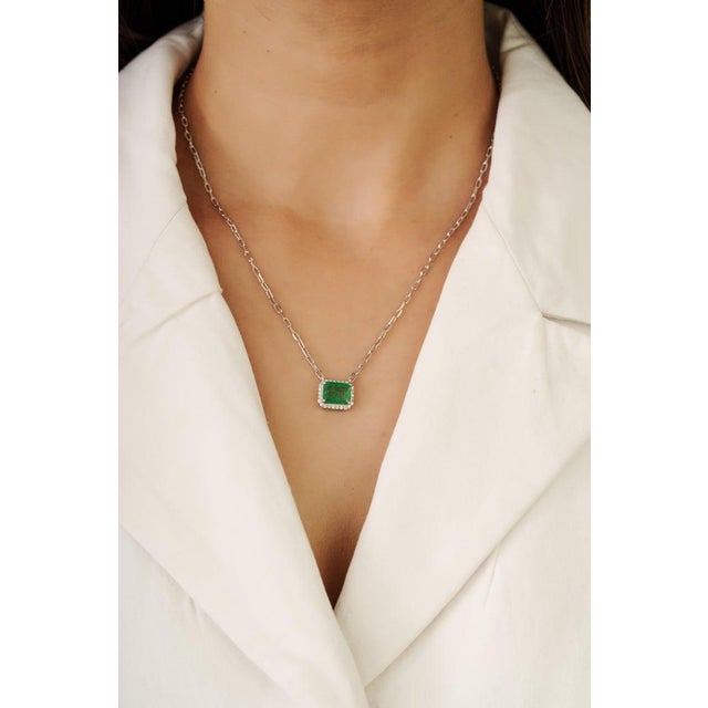 This refined emerald and diamond necklace showcases a beautiful 2.06 carat emerald surrounded by natural diamond accents...