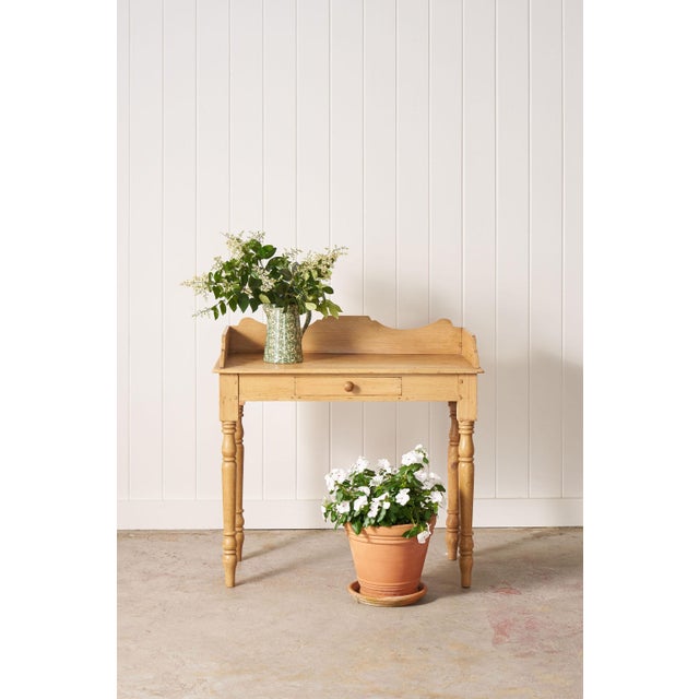 Solid pine writing desk with a single drawer, turned legs, and a warm natural patina.