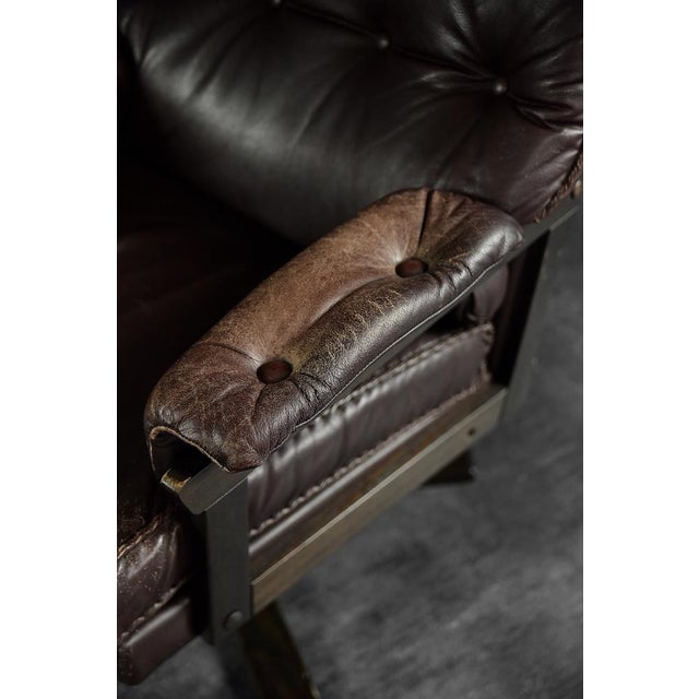 This modernist armchair was made in Denmark during the 1970s. The frame of the armchair is made of wood. It is upholstered...