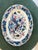 This is an oval ceramic serving platter with a highly decorative, Asian-inspired design. The center features a stylized...