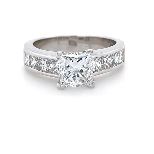 This striking diamond engagement ring is crafted in 18ct white gold and showcases a beautifully proportioned princess-cut...