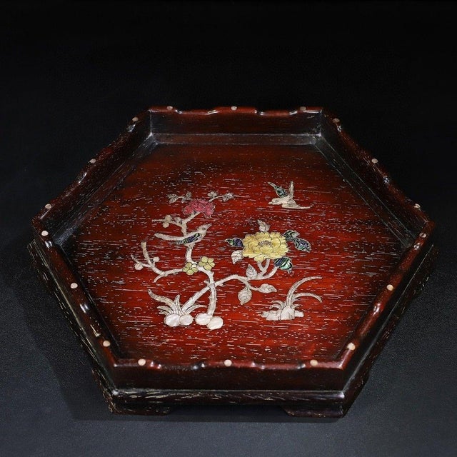 This is a striking, hexagonal wooden tray featuring intricate mother-of-pearl (nacre) inlay work. Crafted from a dark,...