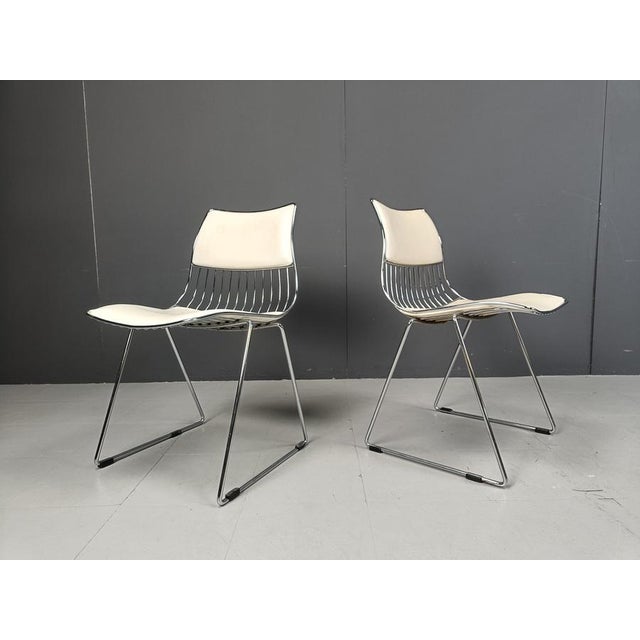 Set of 4 stackable dining chairs designed by Rudi Verelst. The have a heavy wired chrome frame with white faux leather...