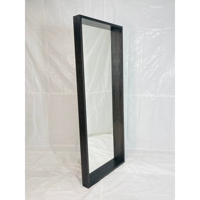 This oversized full-length mirror features a substantial wooden frame with clean architectural lines and a deep profile,...