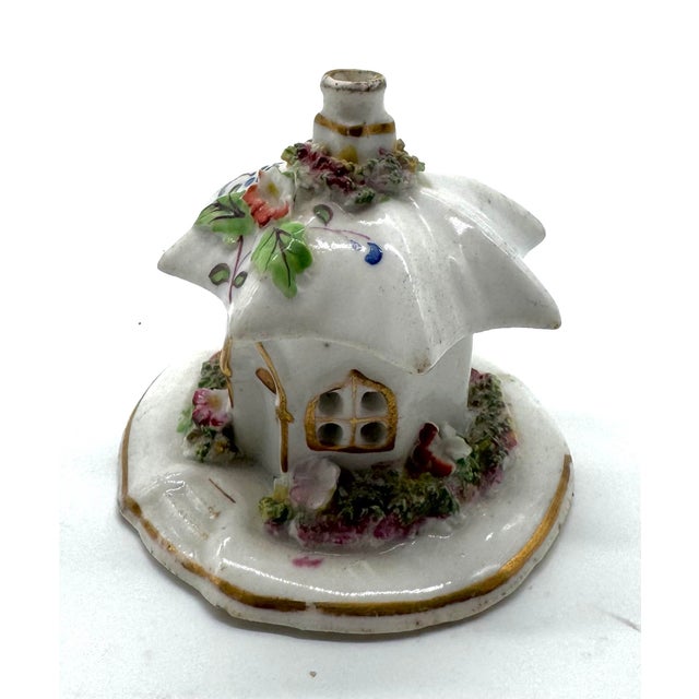 A charming miniature Staffordshire porcelain cottage, richly detailed with a flower-covered garden, painted foliage, and...