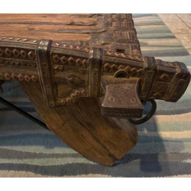 The table is a rustic, antique-style coffee table often repurposed from an Indian or Balinese ox cart or howdah (elephant...