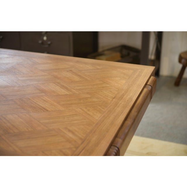 A rectangular table from the 1940s. The veneered top features a geometric design and is framed by a simple border. The...