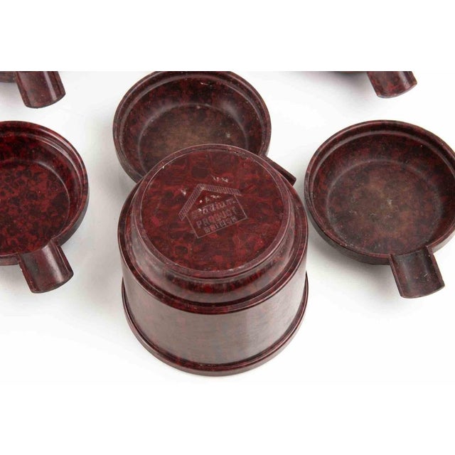 The set includes multiple individual ashtrays that nest or stack inside a central holder or caddy. This design was popular...