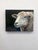 This artwork features a close-up of a sheep, its textured wool rendered with a blend of soft colors that evoke a sense of...