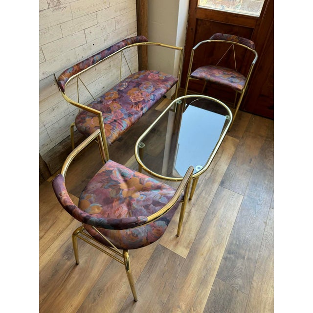 Stylish vintage lounge set featuring a brass frame loveseat, two matching armchairs, and an elegant oval glass coffee...