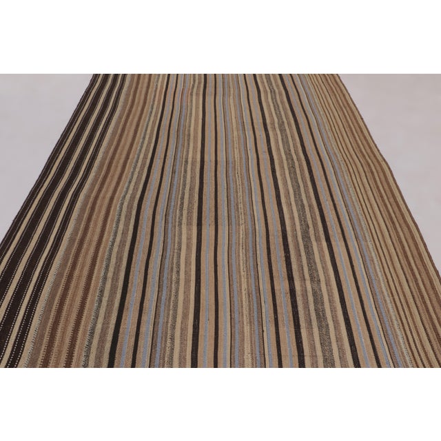 Made with handwoven wool circa 1950-1960, this 7x9 vintage flat-weave Kilim is a particularly unique and sought-after work...