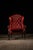 Traditional wingback armchair and coordinating ottoman upholstered in rich oxblood-red leather. The chair features a tall,...