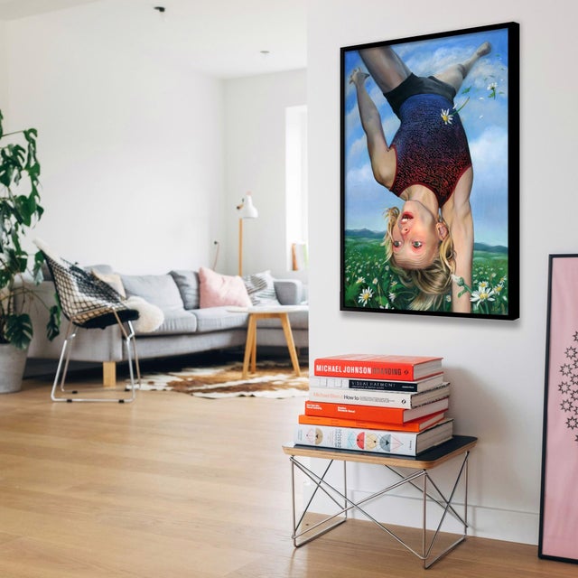This mixed-media piece features a young girl performing a handstand against a backdrop of a vibrant blue sky and a lush...