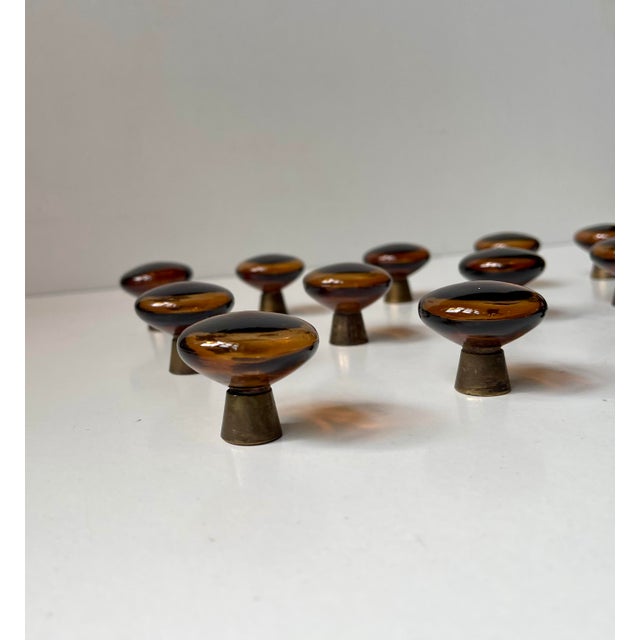 A rare set of 16 hand-blown amber/brown'ish smoke glass door/drawer or cabinet knobs. Base in patinated solid brass. Hand-...