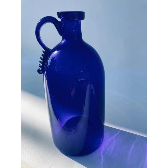 Wonderful blue bottle with profiled and polished rim. the peculiarity of the bottle is the wide handle and the serpentine...