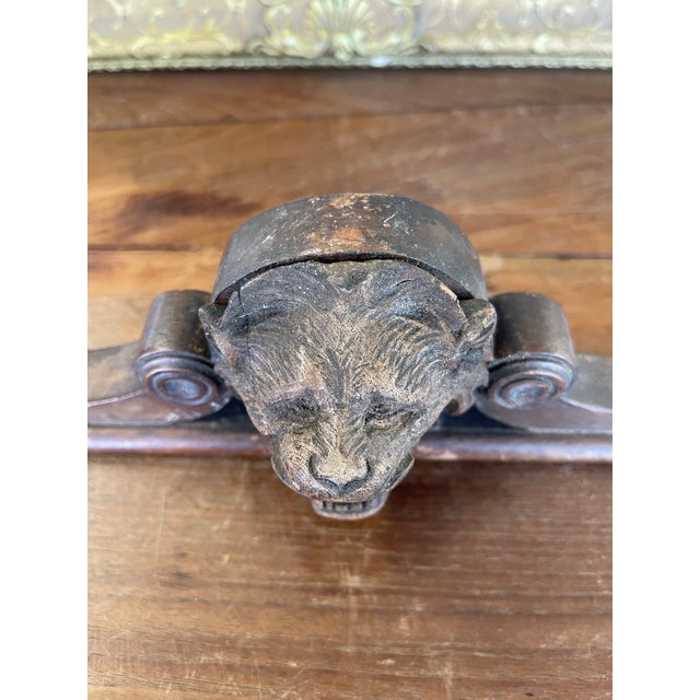 This likely antique wooden architectural fragment features a finely carved lion's head flanked by scroll details. The...