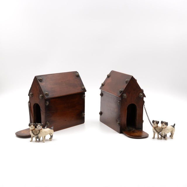 A matched pair of novelty money boxes in the form of miniature doghouses, each constructed of stained wood with a pitched...