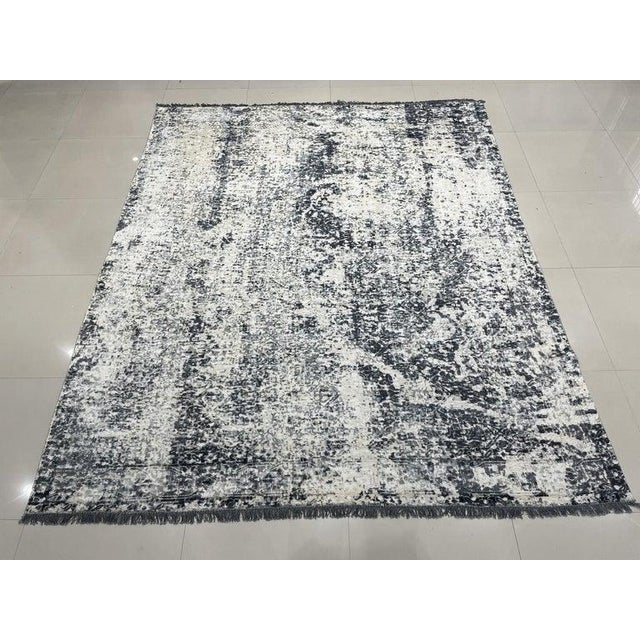 This hand knotted pile rug is crafted from wool and features a primary color palette of ivory, beige, cream, and white....
