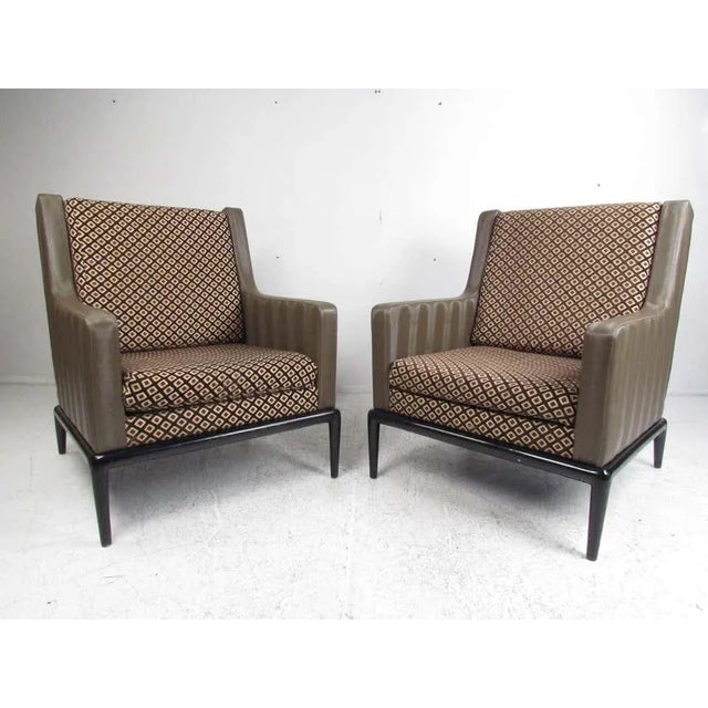 This oversized pair of vintage modern lounge chairs feature a two-tone design with green vinyl and decorative fabric. An...