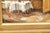 A charming signed oil on canvas depicting a sunlit terrace café scene, with white-clothed tables set beneath a warm red...