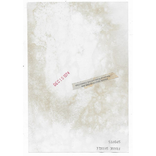 1974 black and white photograph of Woodward Country Club pro Frank Shikle. He's wearing a leisure suit, with a golf course...