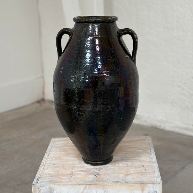 Antique earthenware glazed jug with two handles in a very dark green. Patina and imperfections add to its texture and...