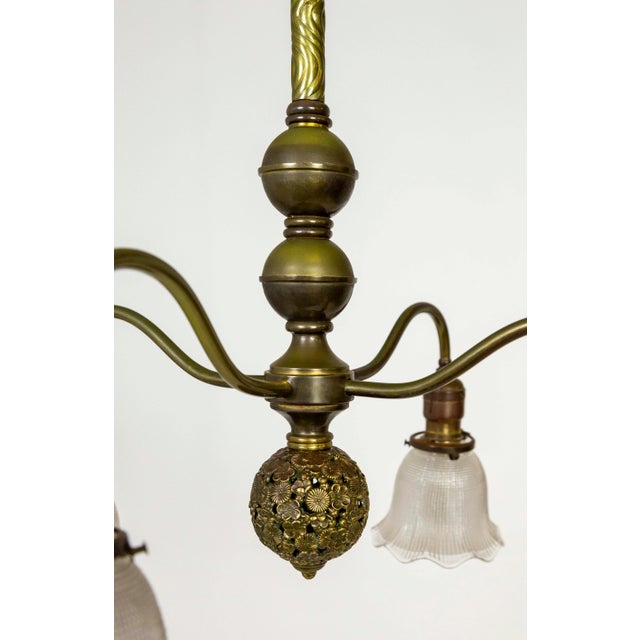An Aesthetic, Victorian, 4-light chandelier with bellflower-shaped, holophane glass shades. The curving, brass arms extend...