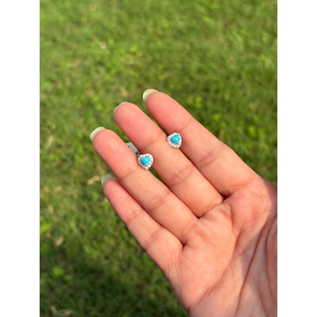 These stud earrings feature a 0.44 carat natural cabochon heart-shaped turquoise, set in 14k white gold with prong...