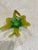 A Murano glass bird candy dish. Bird has its head turned as if preening. Primary colors are green and gold.