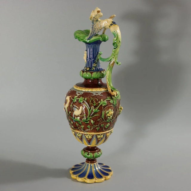 Minton Majolica ewer with a mythological theme which features putti, birds and vine fruits. The ewer has a tapered neck,...