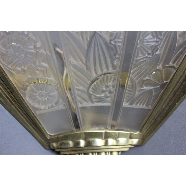 Pair of Art Deco period corner sconces in gilded bronze and pressed glass, decorated with stylized flowers, marked Hettier...