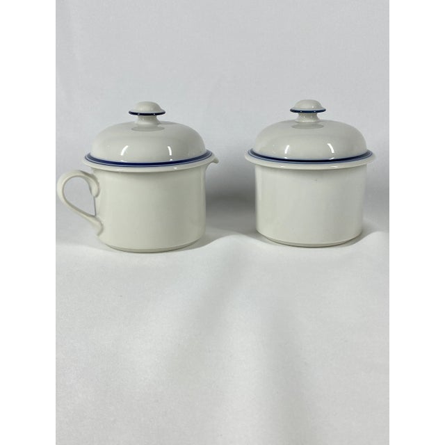 Matching set, sugar bowl and creamer with lid. White ceramic porcelain accented with royal blue bands around the rim. It...