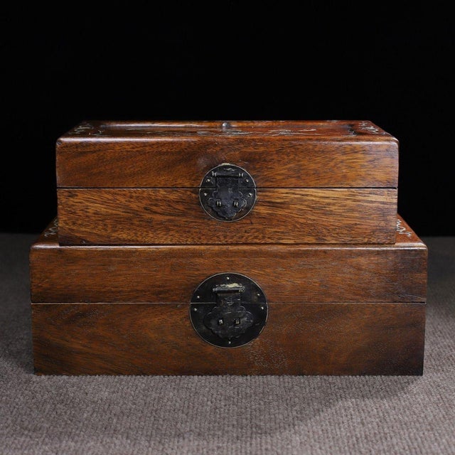 A beautifully crafted set of two Chinese hardwood nesting boxes, likely made of Huali (rosewood). Each box features a...