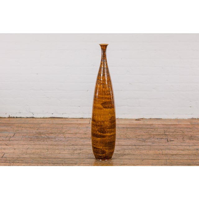 A tall two-tone brown vase with textured accents. This contemporary tall two-tone brown vase is a delicate fusion of...