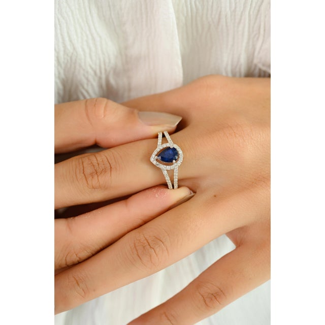 Crafted in luminous 14k white gold, this exquisite ring showcases a striking 0.79-carat pear-cut sapphire at its center —...