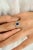 Crafted in luminous 14k white gold, this exquisite ring showcases a striking 0.79-carat pear-cut sapphire at its center —...