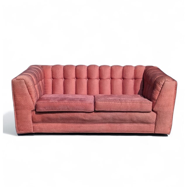 A vintage 1980s postmodern loveseat with boxy low proportions and deep grid tufting in muted rose upholstery. The tailored...