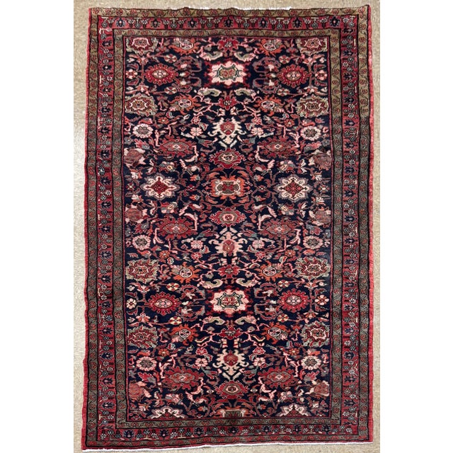 Antique hand-knotted rug from the Nanaj region of western Iran, featuring an allover floral design set on a deep navy...