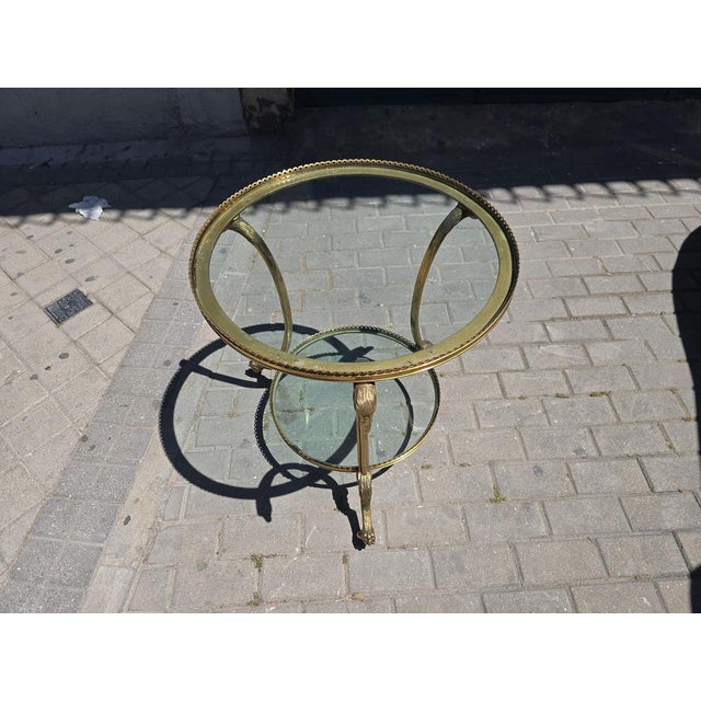 Elegant round side table crafted in gilt bronze and glass during the 1970s, possibly of French manufacture. Combining...