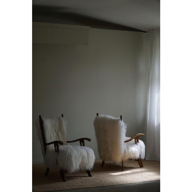 A pair of two rare sculptural Danish modern lounge chairs in solid oak, back and seat reupholstered in longhaired...