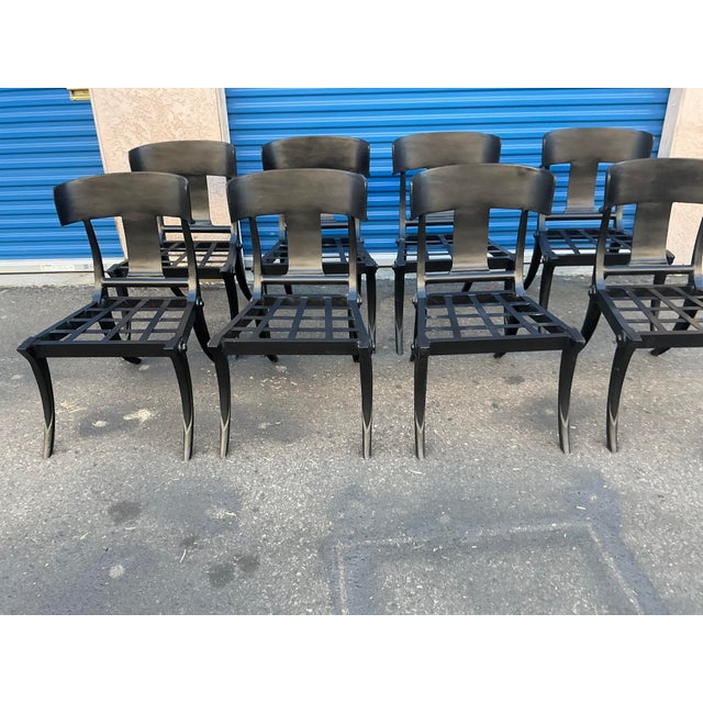 Modern patio Klismos style dining chairs. Set of 8. The chairs are done in iron with a matte black finish. The chairs have...
