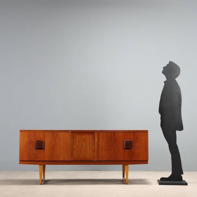Rare sideboard with a retractable illuminated bar compartment, plus bi-folding side doors. Made of teak veneer, fully...