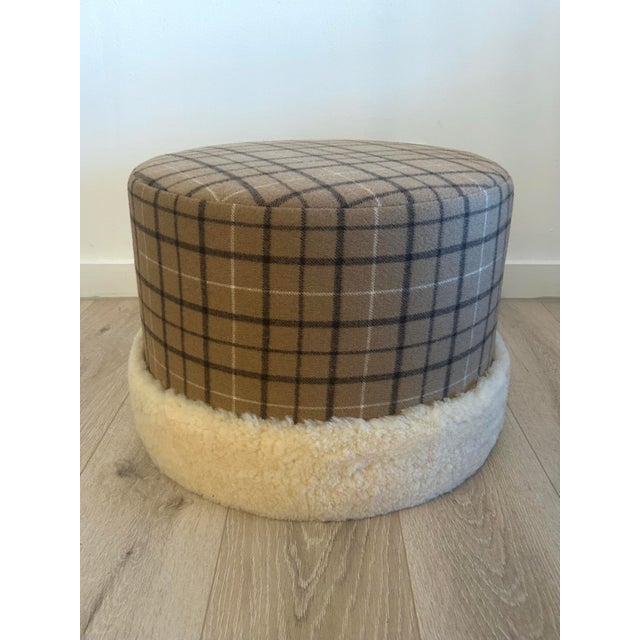 Custom upholstered ottoman in wool plaid. Trimmed in natural colored sheepskin.
