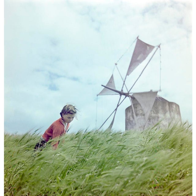 A Windmill In Portugal by Toni Frissell A woman takes a break in a wheat field next to an old windmill, Portugal 1946....