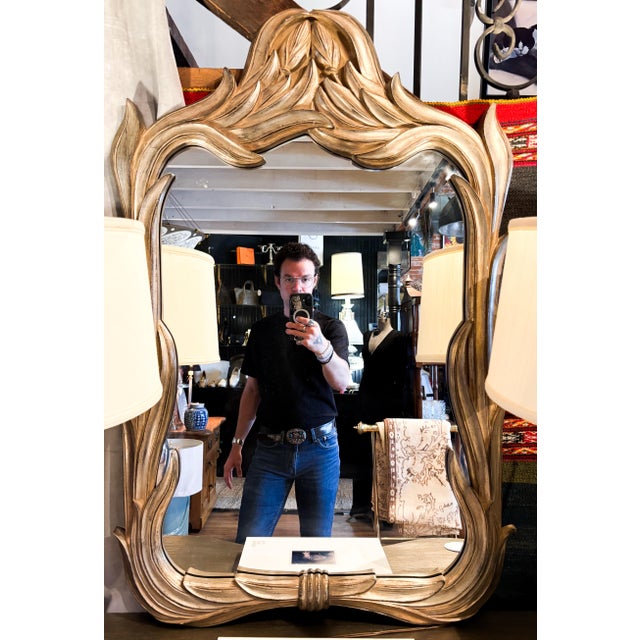 Vintage Wall mirror featuring a mellow silver tone frame that reflects light warmth, with flowing leaf design/carved wood....