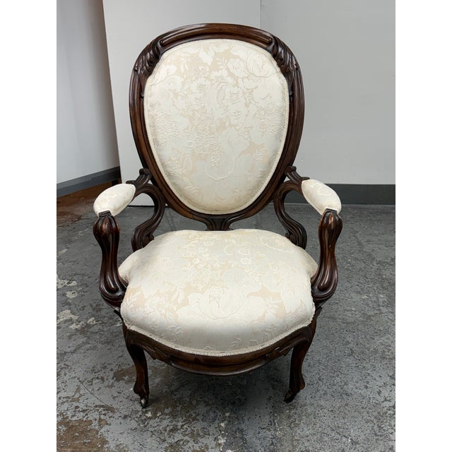 Design Plus Gallery presents a Victorian Rococo Revival carved wood balloon back armchair. The chair has an ornate carved...