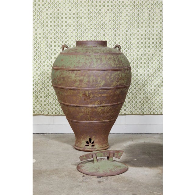 Large urn shaped clay jar with ornamental lid having a bronze and green patina and stamped by the maker. The jar has a...