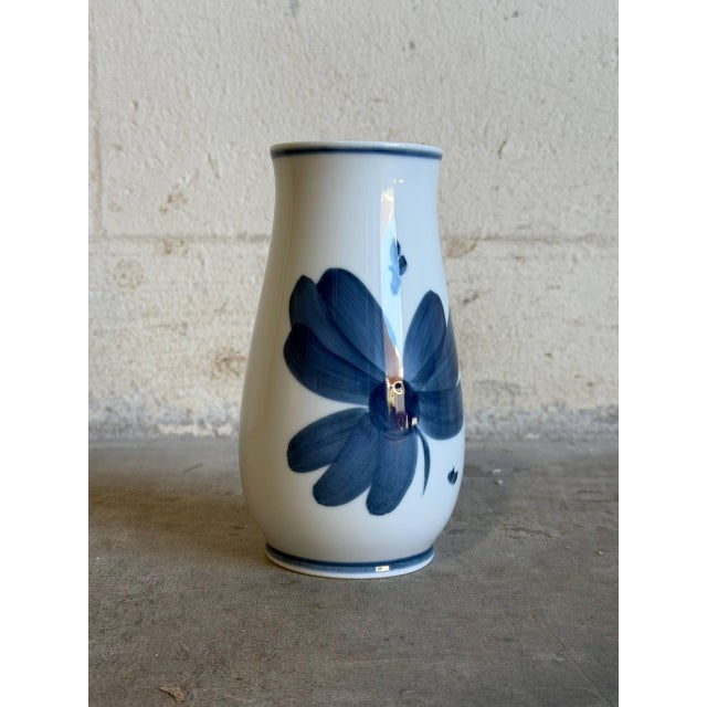 This elegant porcelain bud vase features a striking hand-painted blue anemone flower design against a crisp white...